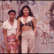 Denijs Lions (Lyon, Danny), Divas latīņamerikāņu meitenes pozē pie graffiti sienas Linča parkā Bruklinā, Ņujorkā (06/1974)